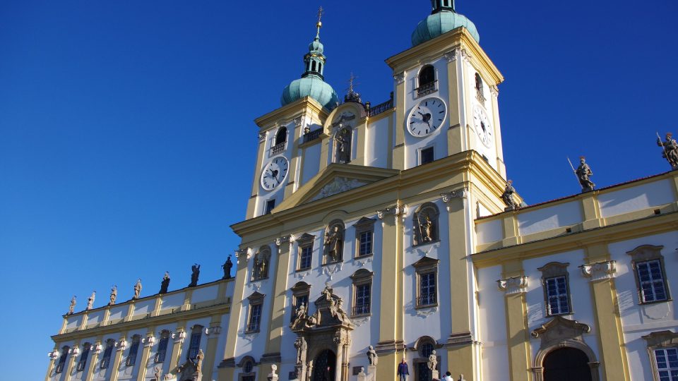 K baroknímu chrámu s dvouvěžovým průčelím přiléhají rezidenční budovy, na jejichž římsách stojí dvanáct apoštolů a dva světci